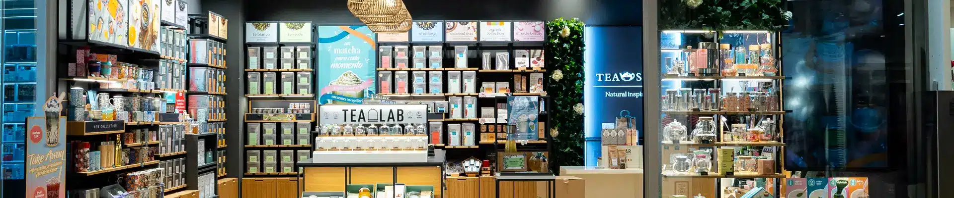 Interior de la tienda de tés Tea Shop en el centro comercial Aragonia, con estanterías de tés e infusiones, la isla Tea Lab y vitrinas de teteras y tazas