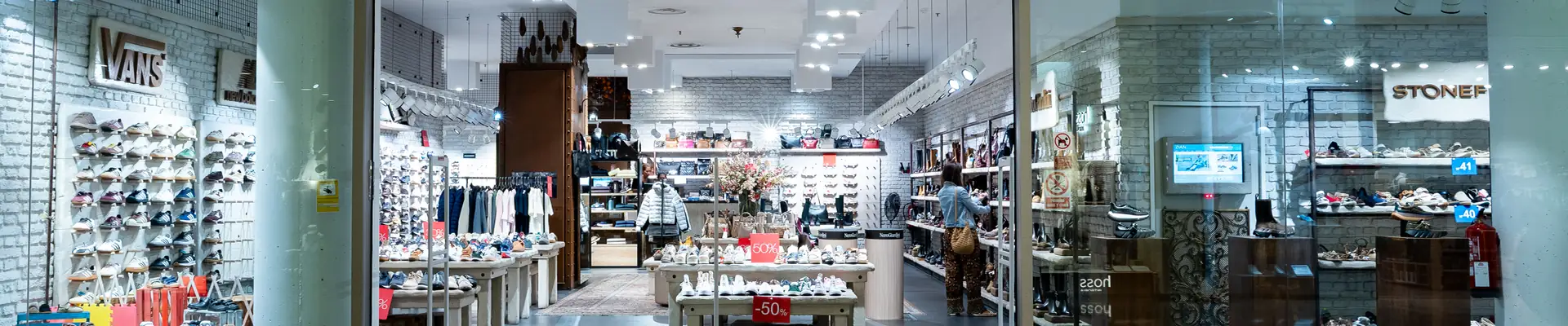 nterior de la zapatería Zian en el centro comercial Aragonia, con paredes de calzado, mesas de exposición de zapatos y córners de marcas como Vans
