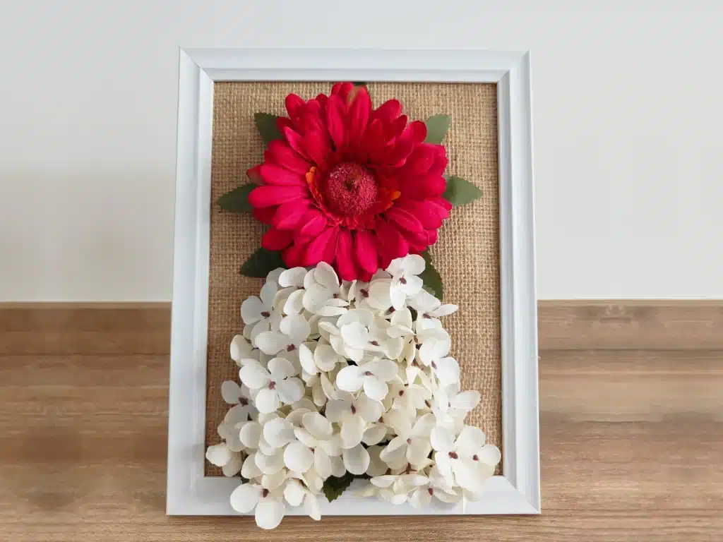 Cuadro floral con gerbera roja y hortensias blancas sobre arpillera, creación del taller Virgen del Pilar de Flores Ohana en Aragonia